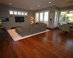 a living room with hard wood floors and lots of windows on the side of the wall