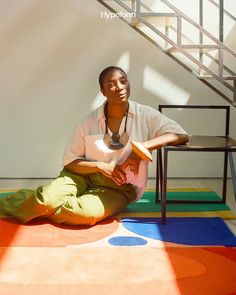 a woman sitting on the ground in front of a stair case