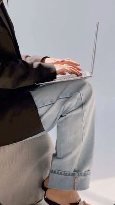 a woman sitting on the ground with her laptop in front of her legs and feet