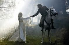 a man riding on the back of a white horse next to a woman in a dress