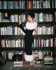 a woman standing in front of a bookshelf