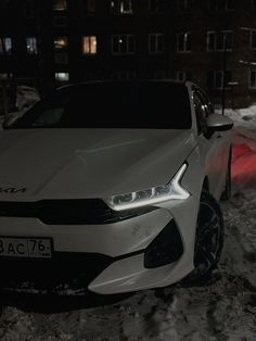 a white car parked in the snow at night