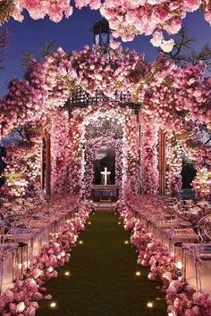 an outdoor wedding setup with pink flowers and candles on the aisle, surrounded by clear chairs