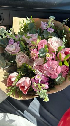 a bouquet of pink flowers sitting on top of a car dash board next to a steering wheel