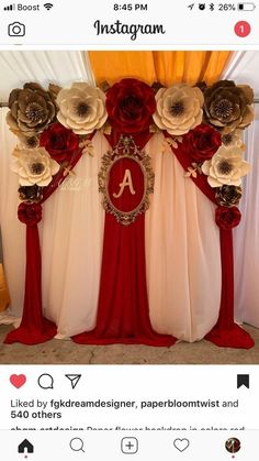 a decorated stage with red and white drapes, gold accents and large paper flowers