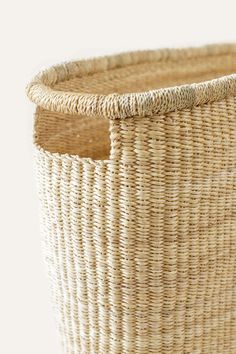 a close up of a woven basket on a white surface with a black cat in the background