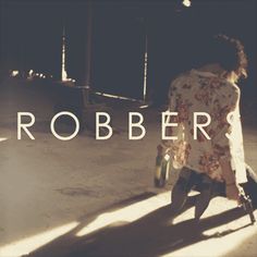 a person sitting on the ground in front of a sign that reads, robbers