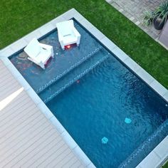 an aerial view of a swimming pool with lounge chairs on the side and grass surrounding it