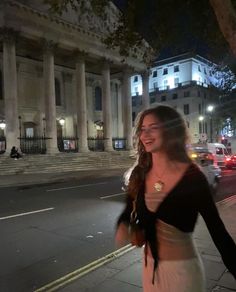 a woman is walking down the street at night