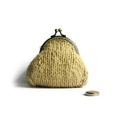 a small purse sitting on top of a white floor next to a coin bag and two coins