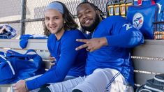 two baseball players sitting on a bench with their arms around each other and pointing at something