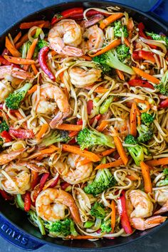 stir fry with shrimp, broccoli, carrots and noodles in a skillet