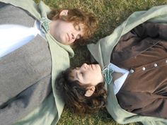 two people are laying on the grass together