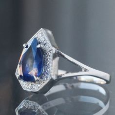 Our classic Phoebe, so beloved because of how her hard exterior frames a softened center, here cradling a 1.79ct ink drop blue sapphire in a brilliant pear cut, highclass spaceship engagement ring to travel through the Borealis particles. A one-of-a-kind beauty, handmade in platinum in our San Francisco Studios by our team of expert jewelers. Currently a size 6.25 and resizable, so please leave your size in the checkout notes! Ink Drop, Pear Cut, Spaceship, Blue Sapphire, Pear, Platinum, San Francisco, Engagement Ring, Sapphire