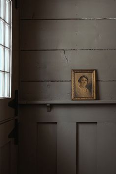 an old portrait is on the shelf in front of a door that has been painted dark gray