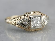 Antique meets modern in this Retro Era ring! This mounting dates to the 1930's, and was likely set with a synthetic sapphire when it was crafted. We've removed the original stone and replaced it with a new, sparkling Square Cut Diamond. This ring sits nearly flush to the finger, and protects the stone quite well. This would work well as an alternative style engagement ring or wedding band! Metal: 14K Yellow and White Gold Gem: Diamond .50 Carats, VVS1 in Clarity, H in Color Accents: 2 Diamonds t Vintage Meets Modern, Late Art, Filigree Ring Gold, Antique Style Rings, Victorian Engagement Rings, Wedding Ring Styles, Filigree Engagement Ring, Band Metal, Alternative Style