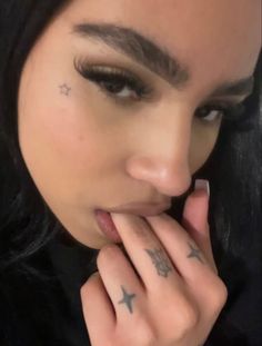 a close up of a person with tattoos on her face and hand near her mouth