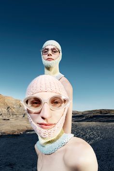 a woman with glasses and a knitted hat on her head is standing in the desert