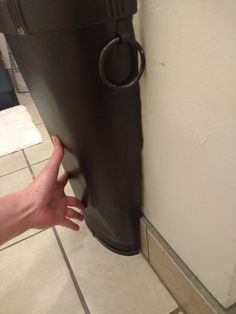 a person is holding their hand up to the side of a rain boot that's leaning against a wall