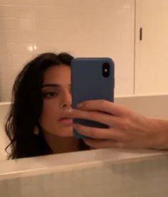 a woman taking a selfie with her cell phone in the bathtub at home