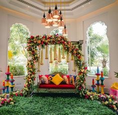 a room decorated in bright colors with flowers and greenery on the floor, including a red couch