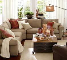 a living room filled with lots of furniture next to a large window covered in curtains