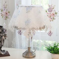 a lamp that is on top of a table next to a potted plant in front of a window