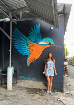 a woman standing in front of a wall with a painting on it's side