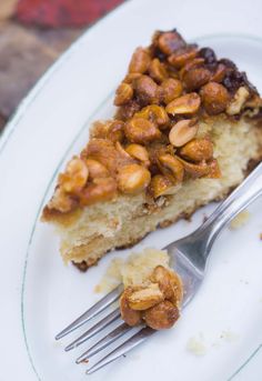 a piece of cake with nuts on top and a fork in the plate next to it