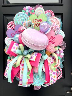 a colorful wreath with lots of different items attached to it's front door for valentine's day