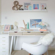 a white desk and chair in a room with pictures on the wall above it,