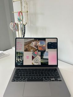 an open laptop computer sitting on top of a white desk next to a phone and jewelry rack