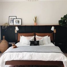 a bed with white sheets and pillows on top of it in a bedroom next to a potted plant