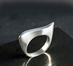 Elegant classic ring featuring a modernist wave design. The ring's fluid curves make an abstract art statement and it has a beautiful handmade look and feel. The ring's inner diameter is about 18.14, making the size a US size 8. The band measures 4 mm wide and is marked 925. The silver band has a few tiny nicks and scratches, consistent with wear and age. When wearing the ring, you don't notice these scratches - what you notice is the beauty of the ring's design and the excellent craftsmanship. Please zoom in each picture to see the tiny dings and scratches that are naturally acquired over time. These can be polished out, however, such marks are part of the ring's history and I'd recommend that you leave the marks and add your own personality and history to the piece :)  The pictures in my Modern Twist Curved Ring With Polished Finish, Modern Twist Curved Rings With Polished Finish, Modern Curved Rings With Polished Finish, Modern Wavy Rings With Polished Finish, Modern Silver Wavy Rings, Modern Curved Jewelry With Polished Finish, Modern Wavy Jewelry For Formal Occasions, Wax Tutorial, Abstract Ring