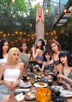 a group of women sitting around a table with food and drinks in front of them