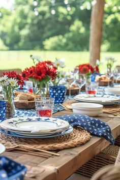 the table is set with blue and white plates, napkins, and red flowers