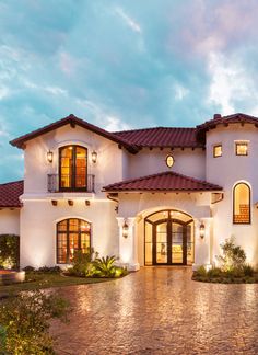 a large white house with lots of windows on it's sides and brick walkway