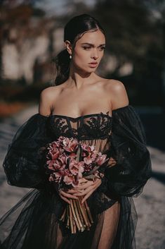 a woman in a black dress holding flowers