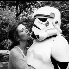 a woman kissing a star wars character in black and white photo with trees in the background