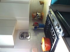 a stove top oven sitting inside of a kitchen next to a counter with utensils on it