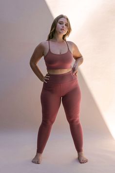 a woman standing with her hands on her hips wearing a pink sports bra and leggings