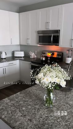 a vase filled with white flowers sitting on top of a kitchen counter