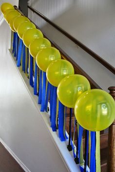 yellow and blue balloons are lined up on the banisters at the bottom of stairs