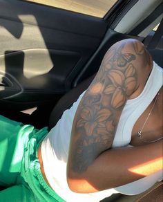 a woman sitting in the back seat of a car with tattoos on her arm and shoulder