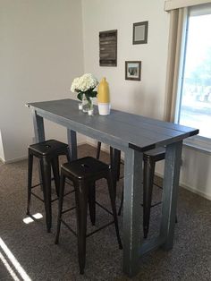 a dining table with three stools in front of it and a vase on top