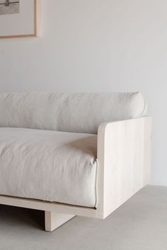 a white couch sitting on top of a cement floor next to a framed picture above it