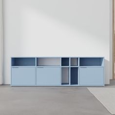 an empty room with a blue shelf next to a white wall and a rug on the floor