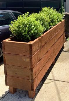 a large wooden planter sitting on the side of a road next to a car