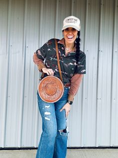 a woman in jeans and a hat holding a brown plate with writing on the side