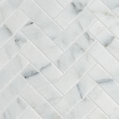 white marble herringbone tile with grey veiners on the edges and diagonals in an irregular pattern